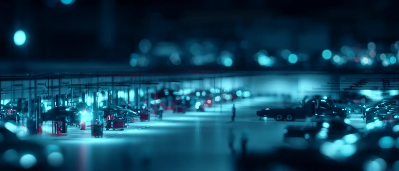 Service bays across a large automotive repair facility at night, with vehicles on lifts and technicians at work